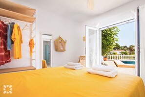 Una stanza con un letto, un armadio, una borsa appesa e vista su una piscina e sul verde circostante.