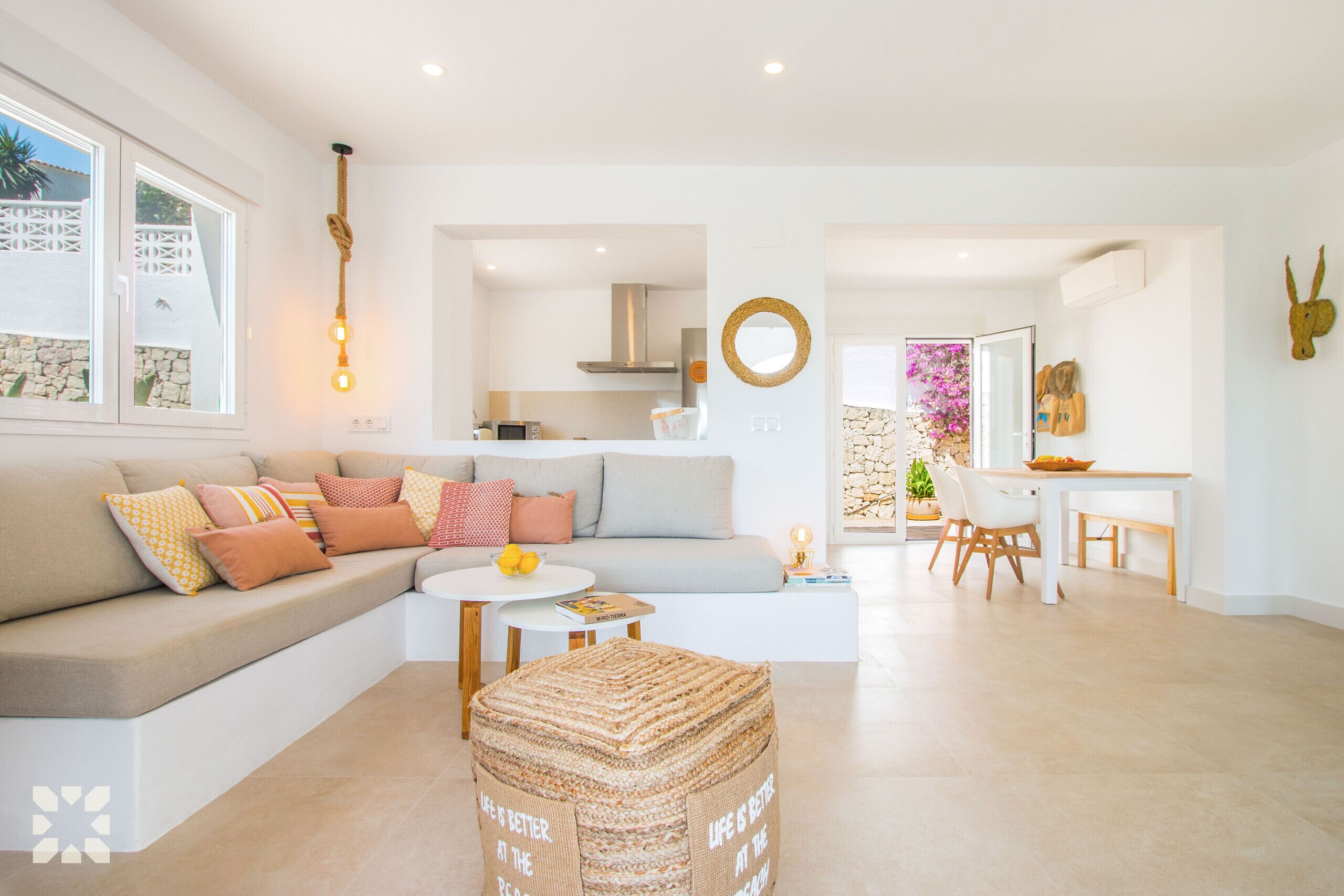 A modern living room with a sofa, ottoman, and dining area.