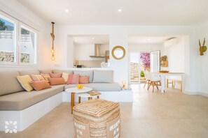 Een moderne woonkamer met een bank, een poef en een eethoek.