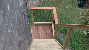 A wooden staircase leading to a covered area with a mesh fence. - Simple and private (Boothbay)