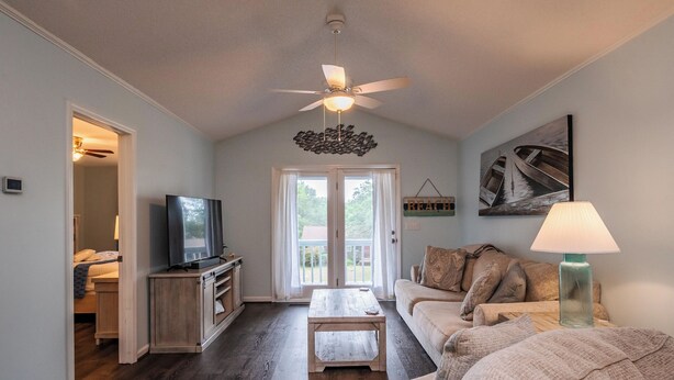 Ein Wohnzimmer mit Deckenventilator, Fernseher, Couchtisch, Sofa und einer Lampe.