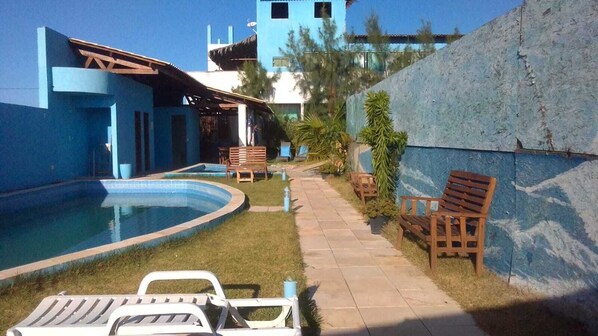 A pool area with lounge chairs and a small garden.