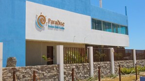A modern building with a blue facade and a sign that reads "Paradise Beach Club Fort."