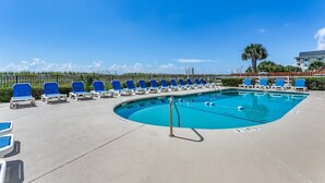 Ein Poolbereich mit blauen Liegestühlen und blauem Himmel.