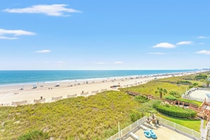 A beach with a wooden boardwalk, a pool area, and a view of the ocean. - 4-bedroom, 3-bathroom, oceanfront unit, sleeps 10 | Ocean Bay Club - 401 (North Myrtle Beach)