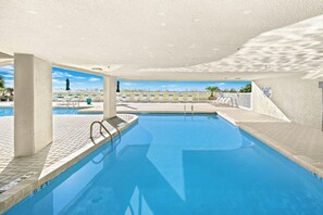 A swimming pool with a tiled deck, a lifeguard sign, and a view of the beach. - 4-bedroom, 3-bathroom oceanfront condo with spacious private balcony - | Ocean Bay Club - 402 (North Myrtle Beach)