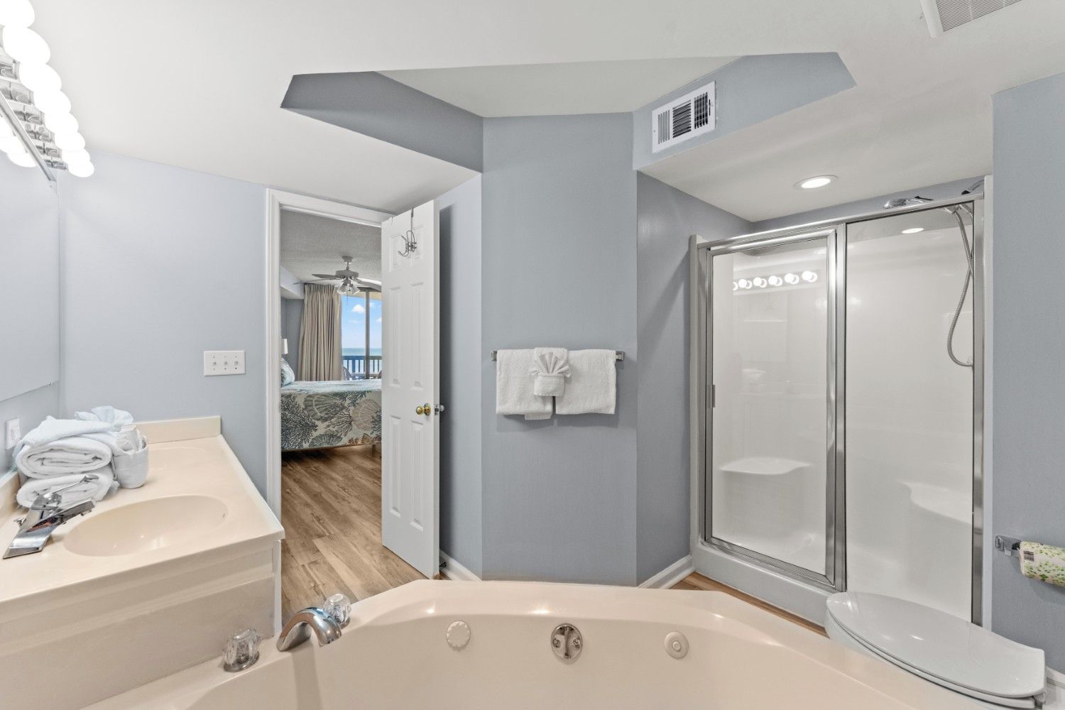 Un baño moderno con bañera, ducha con mampara de vidrio y tocador con lavabo y toallero.