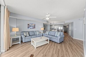 A living room with a sofa set, a coffee table, a lamp, and a ceiling fan. - 4-bedroom, 3-bathroom oceanfront condo with spacious private balcony - | Ocean Bay Club - 402 (North Myrtle Beach)