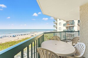 A balcony with a view of the beach, a table, and chairs. - 4-bedroom, 3-bathroom oceanfront condo with spacious private balcony - | Ocean Bay Club - 402 (North Myrtle Beach)