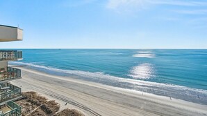 A beachfront property with a balcony overlooking the ocean, a sandy beach, and a clear blue sky. - Oceanfront Penthouse, 4-bedrooms, 4-baths, balcony access from 2 bedrooms | Ocean Bay Club - 1702 PH (North Myrtle Beach)