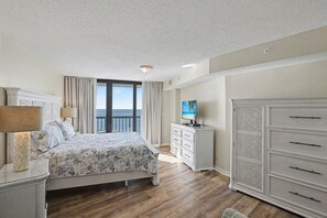 A bedroom with a bed, a dresser, a television, and a view of the ocean. - Oceanfront Penthouse, 4-bedrooms, 4-baths, balcony access from 2 bedrooms | Ocean Bay Club - 1702 PH (North Myrtle Beach)