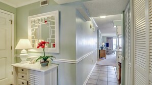 A hallway with a white console table, a mirror, and a potted plant. - Upscale 3-bed, 3-bath, 3rd floor oceanfront condo | Tidemaster - 302 (North Myrtle Beach)