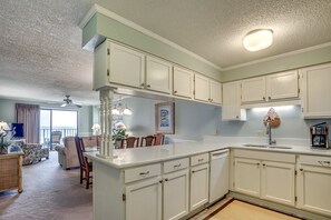 A spacious kitchen with white cabinetry, a large island, and a dining area with chairs and a table. - Upscale 3-bed, 3-bath, 3rd floor oceanfront condo | Tidemaster - 302 (North Myrtle Beach)