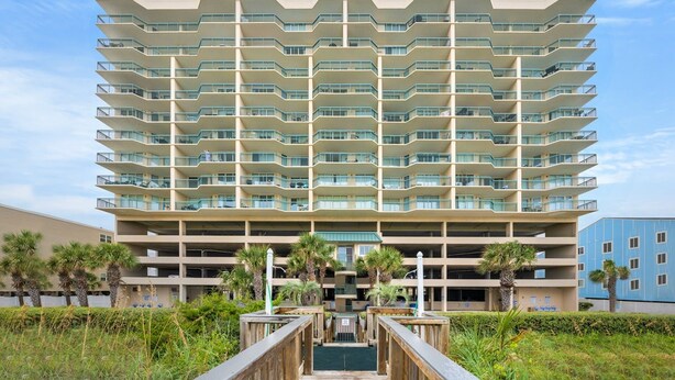 Ein mehrstöckiges Hotel mit modernem Design, mit Balkonen auf jeder Etage, einem zentralen Innenhof und einer Tiefgarage im Hintergrund.