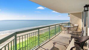 Ein Balkon mit Blick auf das Meer, einem Tisch mit Stühlen und einer Lampe.