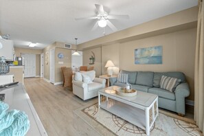 A living room with a sofa, a coffee table, and a dining area with chairs and a table.