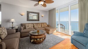 A living room with a sofa, armchairs, a coffee table, and a balcony with a view of the ocean. - Stylish 4-bedroom condo with jetted tub and two king bedrooms | Crescent Shores - N 1101 (North Myrtle Beach)
