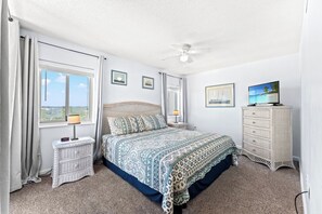 A bedroom with a bed, a nightstand, a dresser, and a ceiling fan.