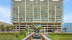 Um hotel de vários andares com design moderno, com varandas em cada andar, um pátio central e uma garagem de estacionamento ao fundo.