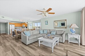 A spacious living room with a grey sofa, a coffee table, and a ceiling fan.