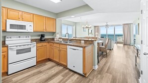 Eine moderne Küche mit Holzschränken, einem Backofen und einem Geschirrspüler.