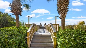 A wooden staircase leading up to a higher level, surrounded by lush green bushes and palm trees. - 3-bed, 3-bath oceanfront condo, updated kitchen, private bathrooms | South Shore Villas - 705 (North Myrtle Beach)