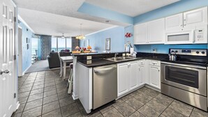A modern kitchen with white cabinets, stainless steel appliances, and a black countertop. - 3-bed, 3-bath oceanfront condo, updated kitchen, private bathrooms | South Shore Villas - 705 (North Myrtle Beach)