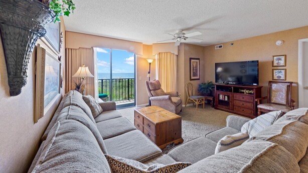 A living room with a sofa set, a wooden cabinet, a television, and a ceiling fan. - First Floor Corner Unit, 3-bedroom/3-bath condo | Beach Club - 1E (North Myrtle Beach)
