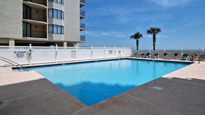 A swimming pool with a white fence, a lifeguard sign, and palm trees in the background. - First Floor Corner Unit, 3-bedroom/3-bath condo | Beach Club - 1E (North Myrtle Beach)