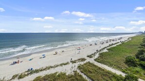 A beach with a sandy shore, a grassy area, and a clear sky. - Well designed 6th floor, 3-bedroom, 3-bath oceanfront condo | Crescent Tower 1 - 601 (North Myrtle Beach)