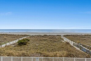 A beach with a wooden fence and a clear view of the ocean.