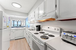 A modern kitchen with white cabinets, a stove, a sink, and a toaster.