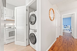 A laundry room with a washer and dryer, an oven, and a bed in the adjacent bedroom. - Cool condo with unique design, 3 bedrooms | Crescent Sands - 5-F (North Myrtle Beach)