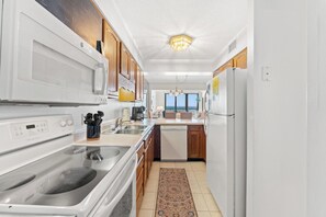 Une cuisine moderne avec des appareils électroménagers blancs, des meubles en bois et un tapis à motifs.