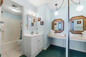 A bathroom with a bathtub, a sink with a mirror, and a toilet.