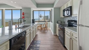 Cozinha moderna com uma ilha grande, eletrodomésticos embutidos e vista para o oceano.