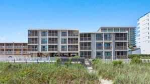 A multi-story hotel with balconies, a pool area, and a beach view. - Ocean View Condo in Crescent Beach | Crescent Beach Villas - 108 (North Myrtle Beach)