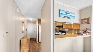 A compact kitchen with wooden cabinets, a built-in stove, and a small countertop. - Ocean View Condo in Crescent Beach | Crescent Beach Villas - 108 (North Myrtle Beach)