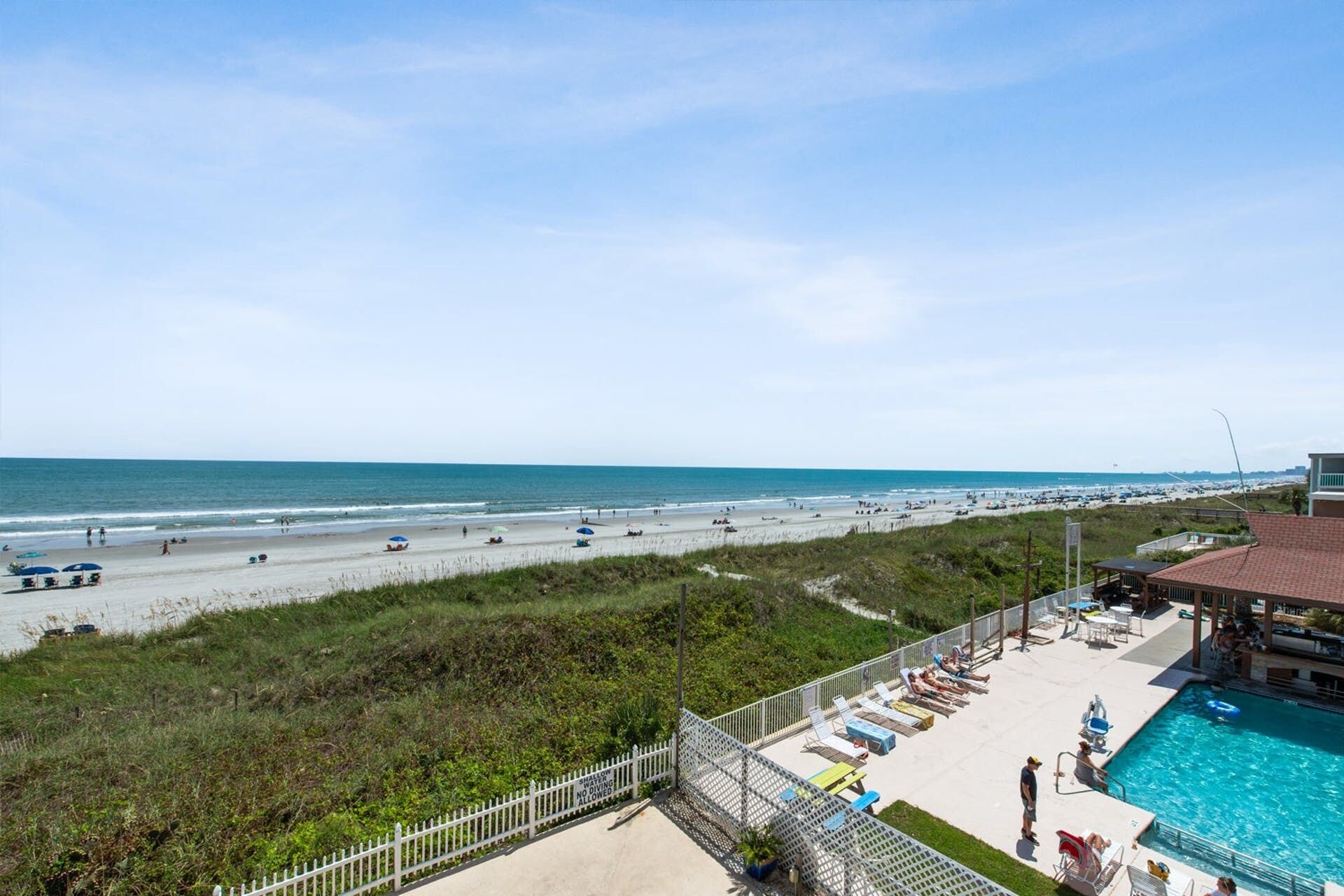 A beach view with a swimming pool and lounge chairs.