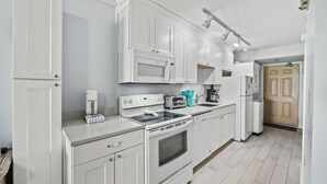 Una cocina moderna con armarios blancos, microondas, estufa y tostadora.