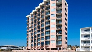 A multi-story hotel with a flat facade, numerous balconies, and a sandy beachfront setting. - 2-bedroom Corner Unit with private balcony | Carolina Reef - 301 (North Myrtle Beach)
