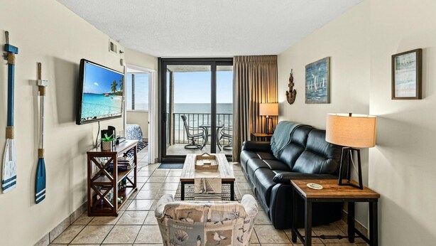 A hotel room with a balcony, a TV, a sofa, a coffee table, and a desk. - 2-bedroom Corner Unit with private balcony | Carolina Reef - 301 (North Myrtle Beach)