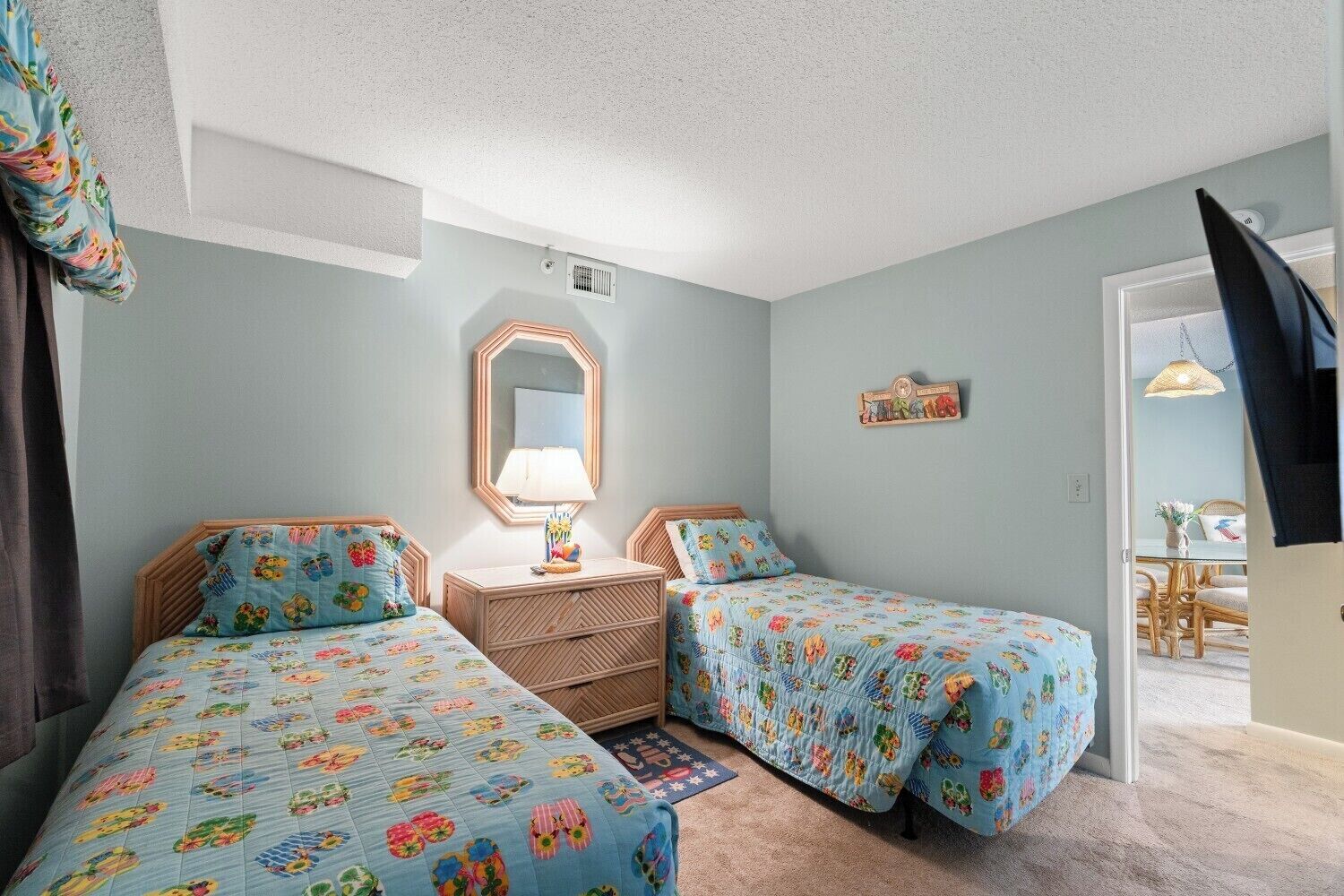 Une chambre avec deux lits, une table de chevet, un miroir et une porte donnant sur un coin repas.