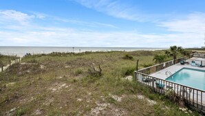 A beach view with a pool area, including a fenced deck and lounge chairs. - 3-bedrom, 2.5 bath, 1st floor oceanfront condo | Dunescape - 101 (North Myrtle Beach)