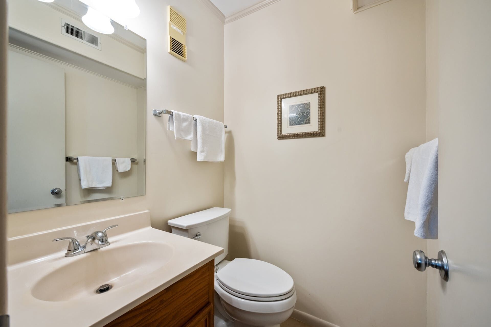Un baño con lavabo, espejo, inodoro y toallero.