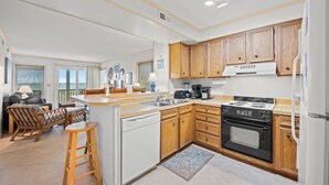 A kitchen with wooden cabinets, a dishwasher, a stove, and a coffee maker. - 3-bedrom, 2.5 bath, 1st floor oceanfront condo | Dunescape - 101 (North Myrtle Beach)