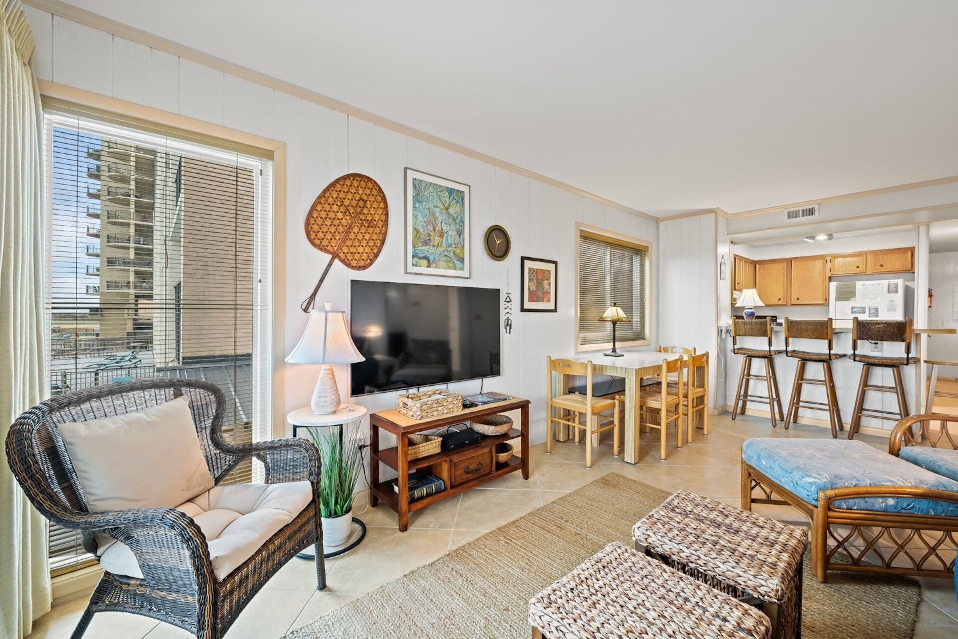 A living room with a TV, wicker furniture, and a dining area with wooden chairs and a table.