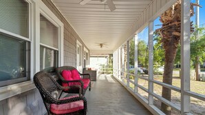 A covered porch with wicker chairs and a ceiling fan. - 3-bedroom Beach Cottage, 4th Row, Large Back Deck and screened in porch | Mermaid Cottage - 4000 (North Myrtle Beach)