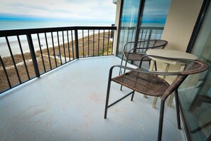A balcony with a view of the beach and ocean, featuring wicker chairs and a small table. - Upscale 4th floor, 3-bed, 3-bath oceanfront condo | Crescent Tower II - 407 (North Myrtle Beach)