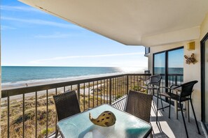 A balcony with a glass table and chairs, overlooking a beach and ocean. - Upscale 4th floor, 3-bed, 3-bath oceanfront condo | Crescent Tower II - 407 (North Myrtle Beach)